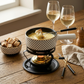 Exklusives 5-teiliges Käsefondue-Set «Element Dots» für 2 Personen. Modernes Design mit Goldrand, gefüllt mit cremigem Käse, auf rustikalem Holztisch mit Weinbegleitung